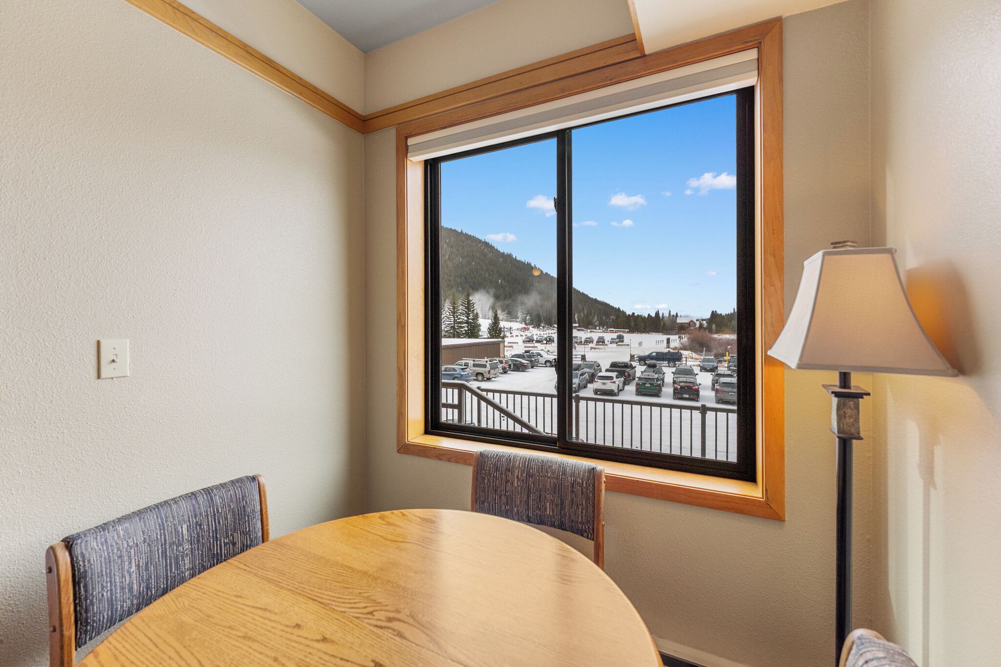 A room with a large window offering a view of a parking lot and a mountainous landscape.