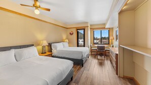 A hotel room with two beds, a desk, a chair, a lamp, and a view of the outdoors. - S2736-0 (Keystone)