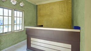Ein Empfangsschalter mit grüner Wand und einem Fenster mit mehreren Scheiben.
