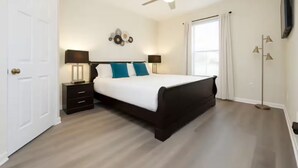 Ein Schlafzimmer mit Bett, Nachttischen, Deckenventilator und Stehlampe.