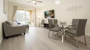 Un salon moderne comprenant un canapé, une table à manger, des chaises et un ventilateur de plafond.