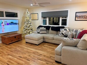 A living room with a sectional sofa, a television, a Christmas tree, and a ceiling fan. - Okemo House (Ludlow)