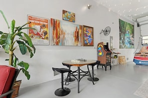 Ein Zimmer mit einem Schachbrett, Kunstwerken an den Wänden, einer Pflanze und einem Ventilator.