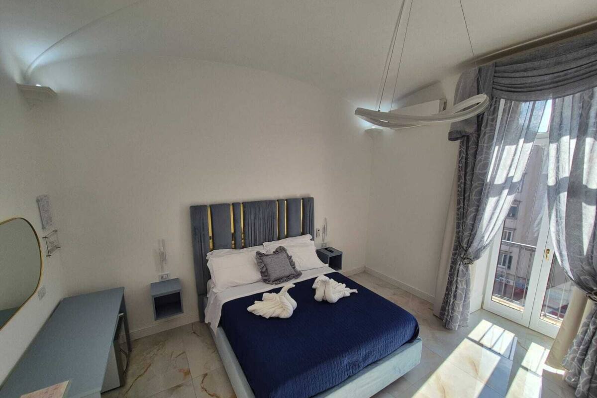 A bedroom with a bed, bedside tables, a mirror, and a window with curtains.