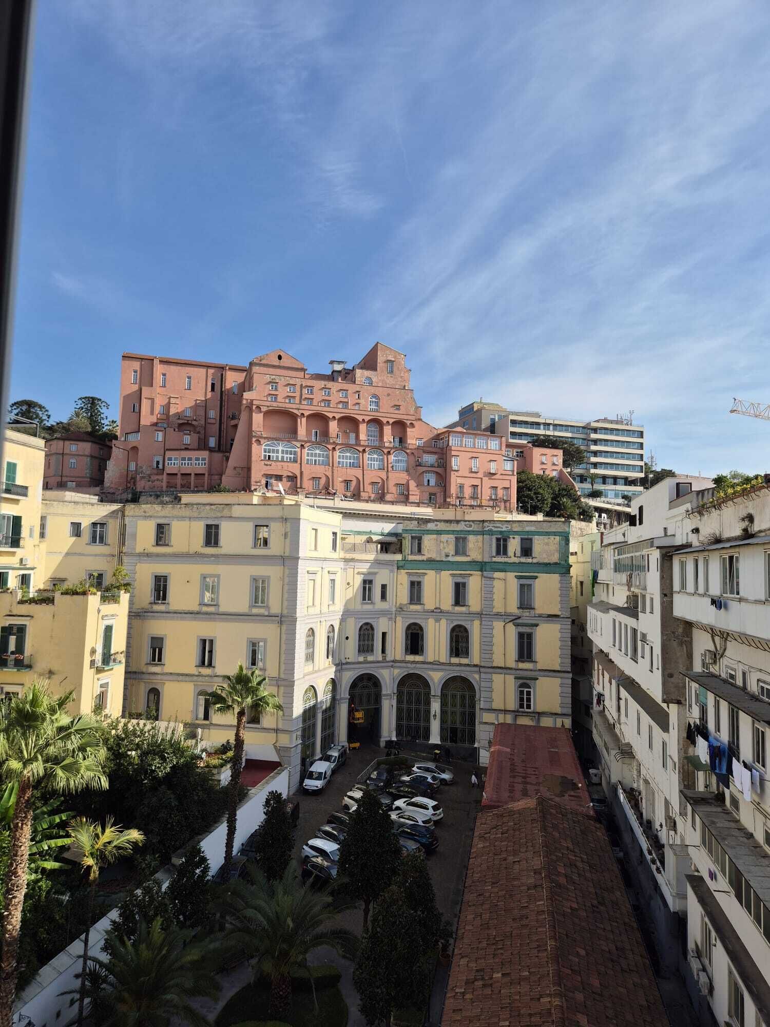 A view of a building with multiple floors and a courtyard with parked cars.