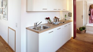 A modern kitchen with white cabinetry, a wooden countertop, and a built-in sink. - KÖNIGSschlaf's barrier-free apartment: Chic, spacious, central! (Konstanz)