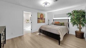 A bedroom with a bed, a dresser, a plant, and a painting on the wall. - Peaceful Retreat Four Bedroom home in charming Shenandoah (Shenandoah)