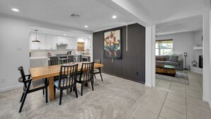 A modern kitchen with white cabinets, a wooden dining table, and a large painting on the wall. - Peaceful Retreat Four Bedroom home in charming Shenandoah (Shenandoah)