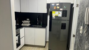 A compact kitchen with white cabinets, a stainless steel refrigerator, and a small countertop. - Best experience: location, comfort and price (Ibagué)