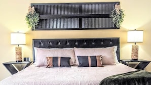Een bed met een gebedruid sprei, twee kussens en een donker hoofdbord.