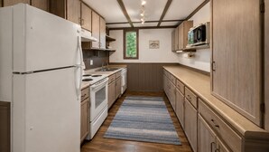 A compact kitchen with a refrigerator, stove, microwave, and wooden cabinets.