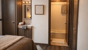 A bedroom with a bed, a bathroom with a bathtub, and a shower.