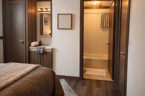Une chambre avec un lit, une salle de bain avec une baignoire et une douche.