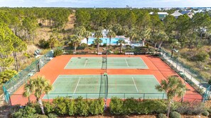 A tennis court surrounded by greenery and a building with a pool. - Vitamin Sea, 3 Min Walk to the Beach, Sleeps 13 (Gulf Shores)