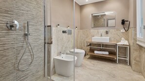 A modern bathroom with a glass shower enclosure, a white sink, and a toilet.