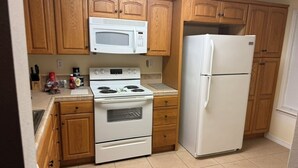 A kitchen with wooden cabinets, a microwave, a stove, and a refrigerator. - 2-bedroom house in wonderful Demopolis with cool AC (Demopolis)
