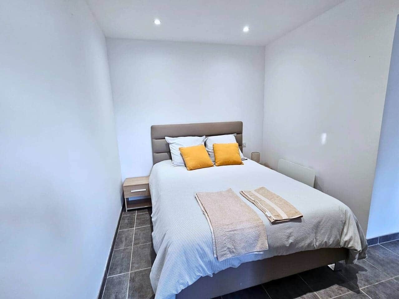 A neatly arranged bedroom with a bed, pillows, and a bedside table.