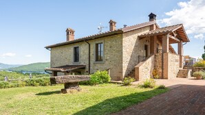 A stone house with a wooden staircase, a small porch, and a view of the landscape.