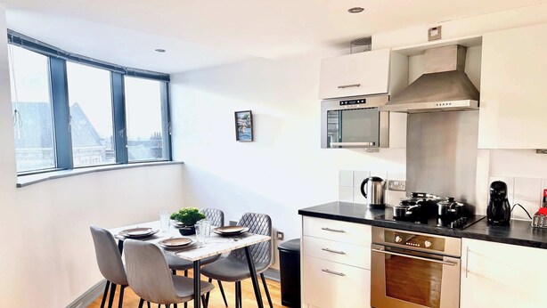 Une cuisine moderne avec un coin repas, de grandes fenêtres et une vue sur le paysage urbain.