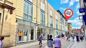 Une rue animée en ville, bordée de boutiques et fréquentée par de nombreux piétons.