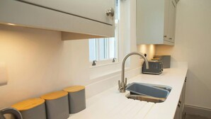 Una cocina moderna con encimera blanca, un lavabo de acero inoxidable y un tostador.