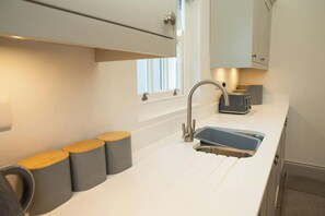 A modern kitchen with a white countertop, a stainless steel sink, and a toaster. - Gelli Genlas, Llanarth (New Quay)