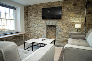 Ein Wohnzimmer mit Steinwand, Kamin, Flachbildfernseher, Sofa, Couchtisch und Lampe.