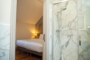 Une chambre à coucher avec un lit, une lampe de chevet et une cabine de douche en marbre.