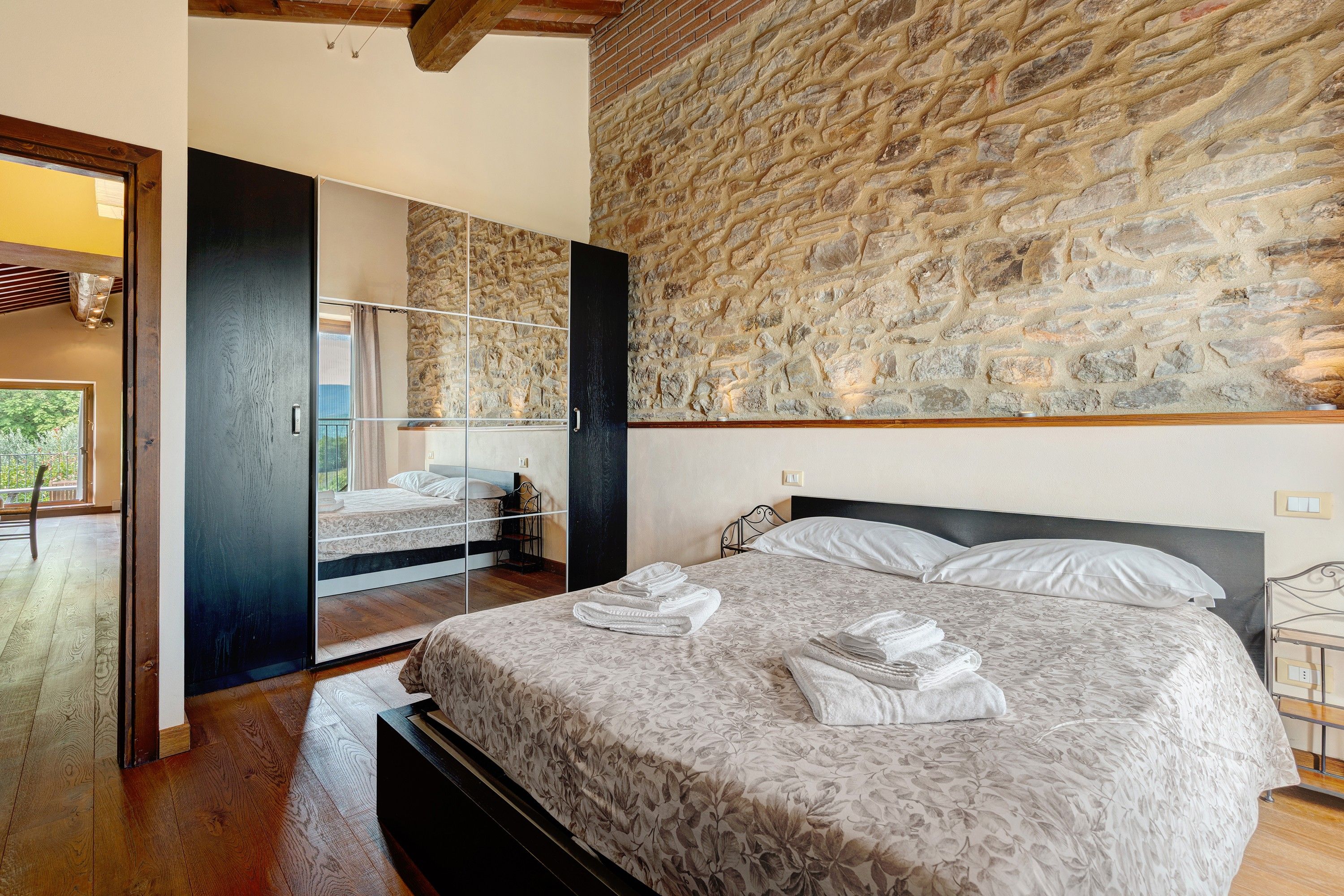 Una camera da letto con un letto grande, un muro in pietra e un soffitto in legno.