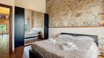 Una camera da letto con un letto grande, un muro in pietra e un soffitto in legno.