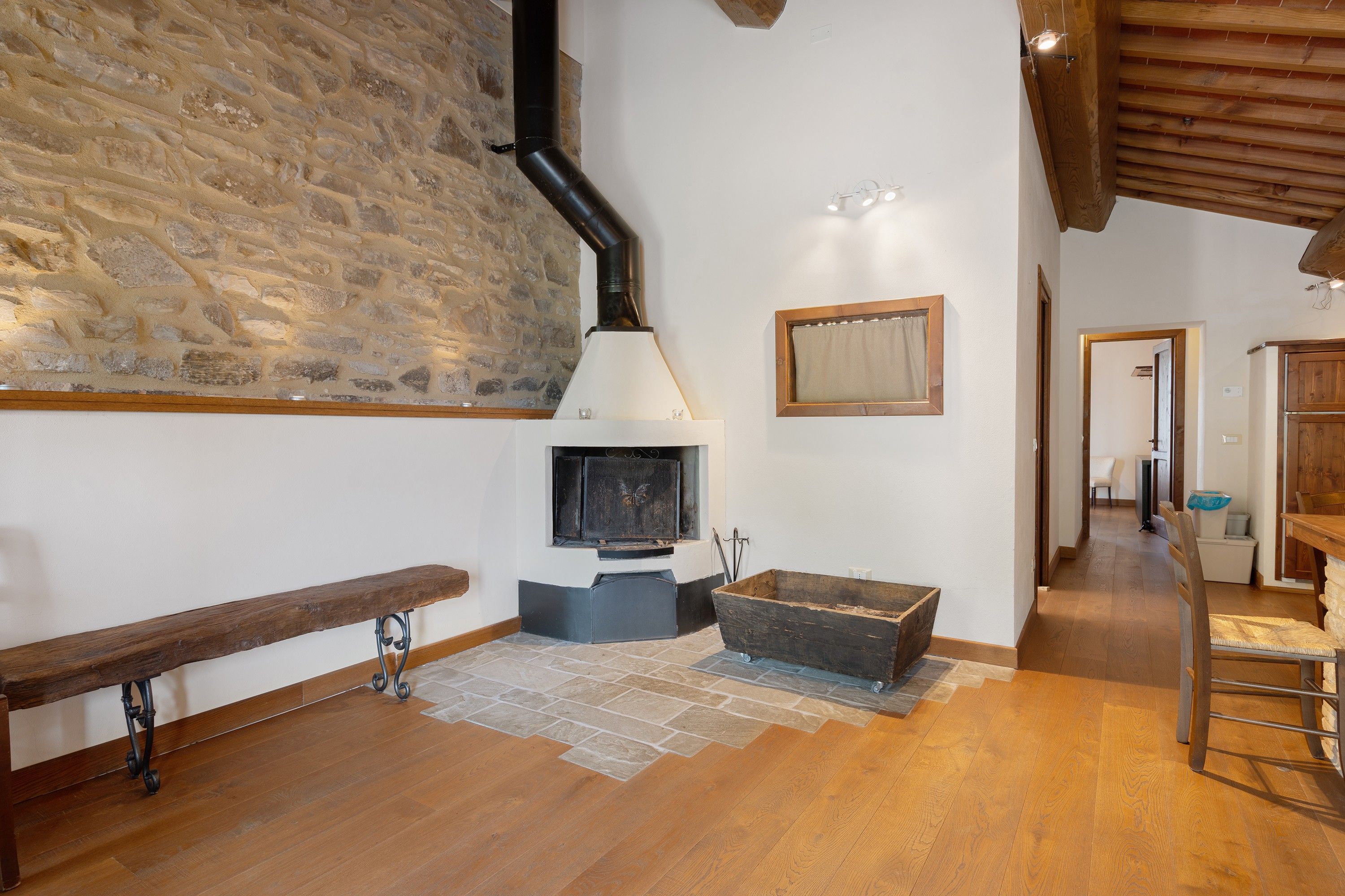 A cozy room with a stone wall, a fireplace, a bench, and a wooden table.