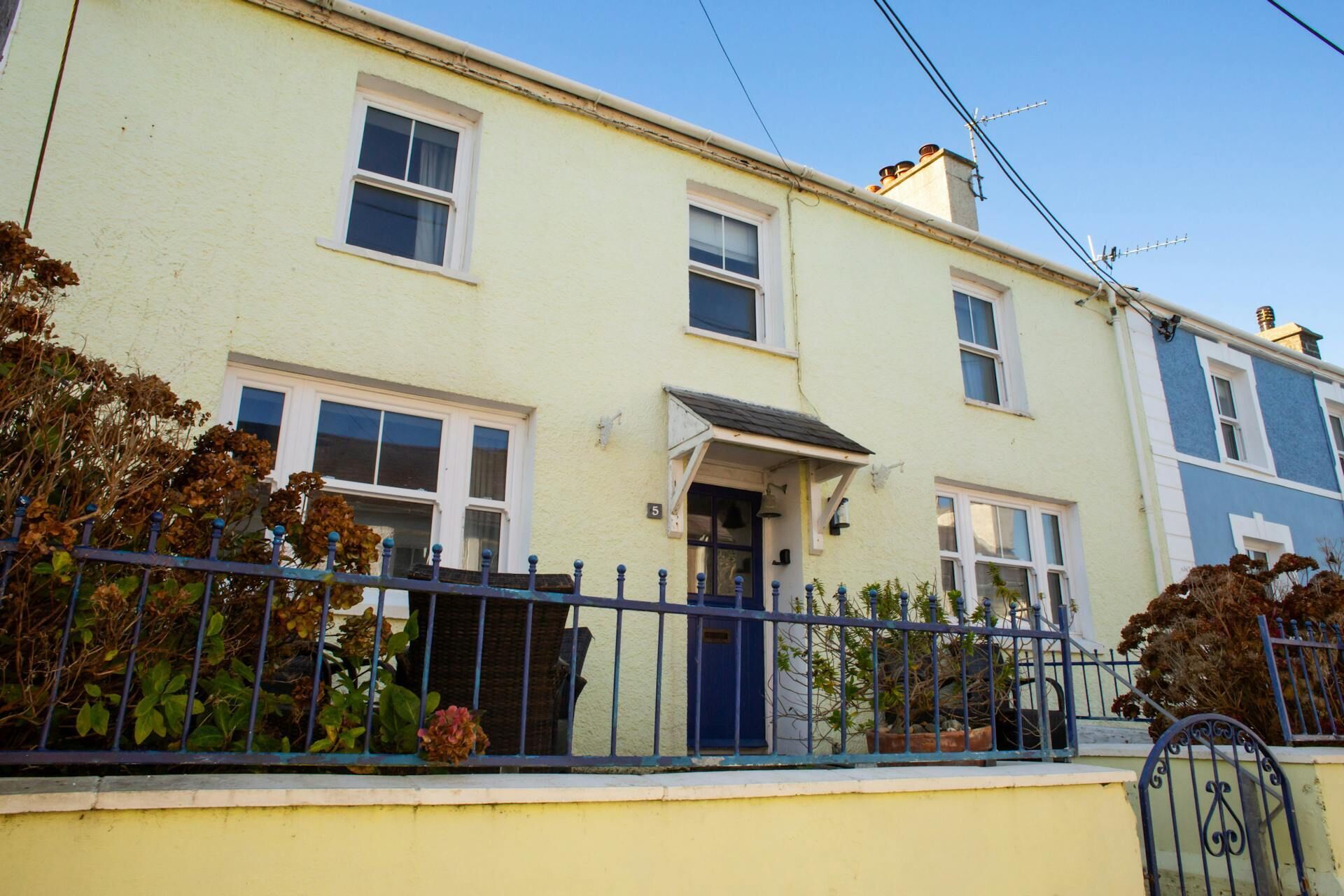 A row of terraced houses with a front door, windows, and a blue metal fence.