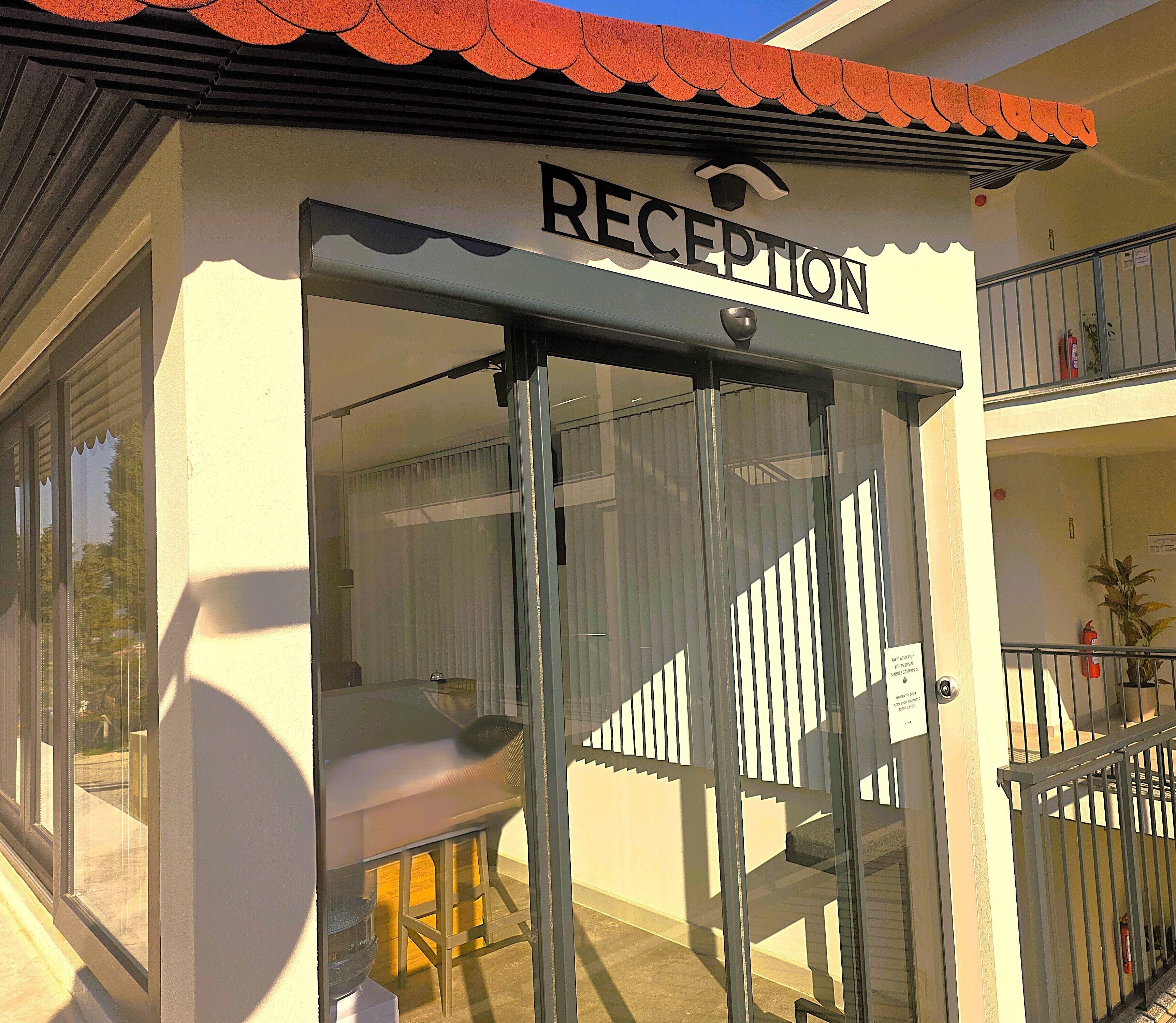 Un espace d’accueil doté d’une porte en verre, d’une enseigne au-dessus et d’un balcon avec une balustrade.
