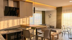 Une cuisine moderne avec un coin repas, comprenant un plan de travail en granit, un four encastré et une table à manger en bois avec des chaises.