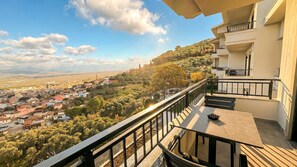 A balcony with a table and chairs, overlooking a town with buildings and trees. - TopTepeHome (Tire)