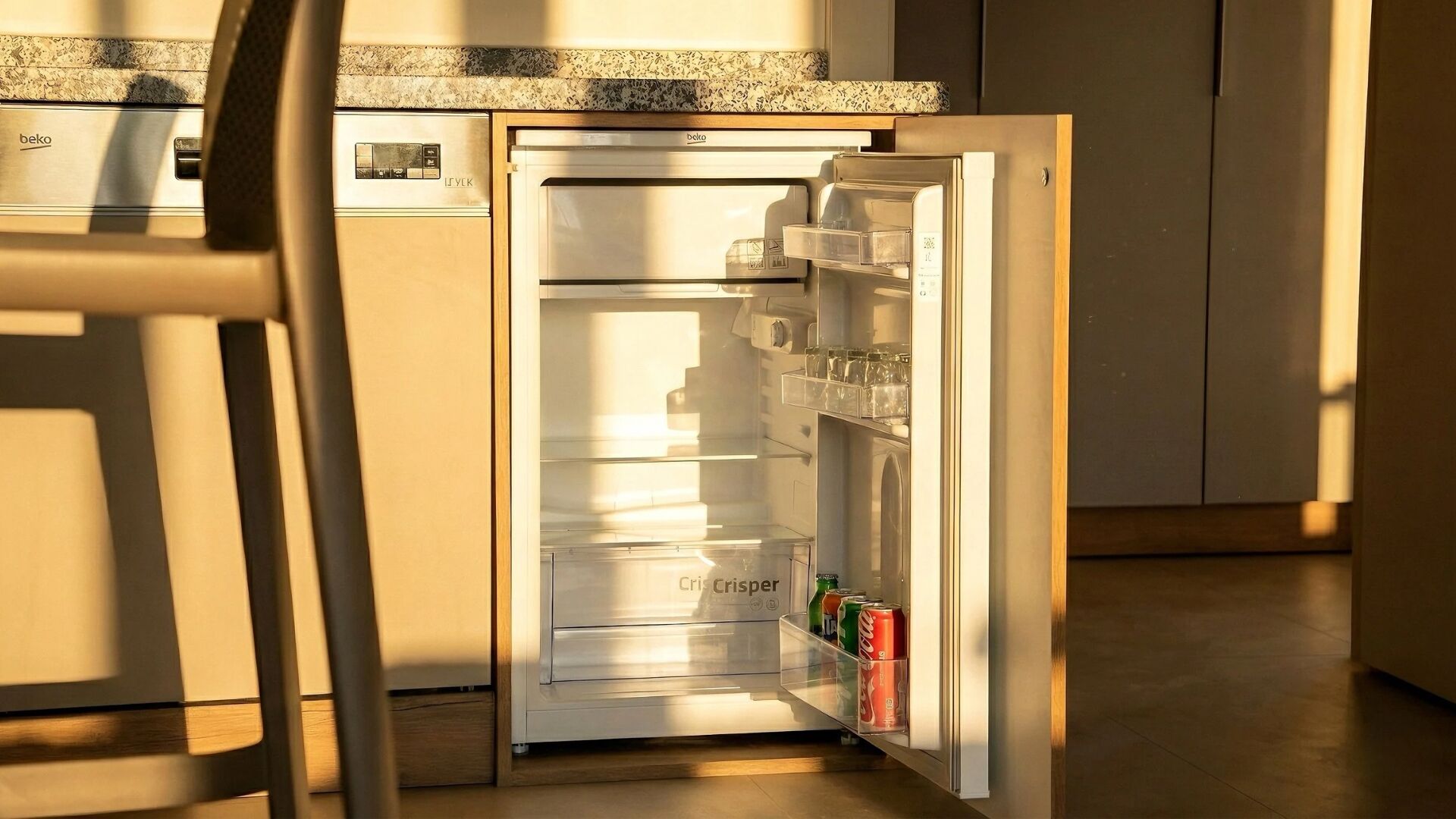 Un refrigerador abierto con un compartimento congelador a la izquierda y un estante con bebidas.
