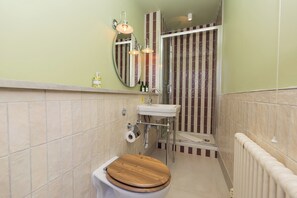 A bathroom with a toilet, sink, mirror, shower, and striped tiles. - Super central room in the heart of Bath - Pass the Keys (Bath)
