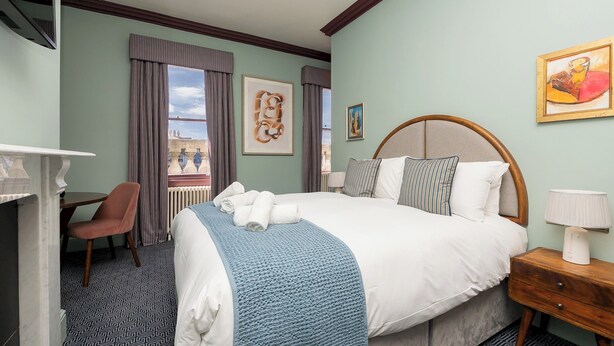 Een hotelkamer met een groot bed, een bureau, een stoel en kunstwerken aan de muur.