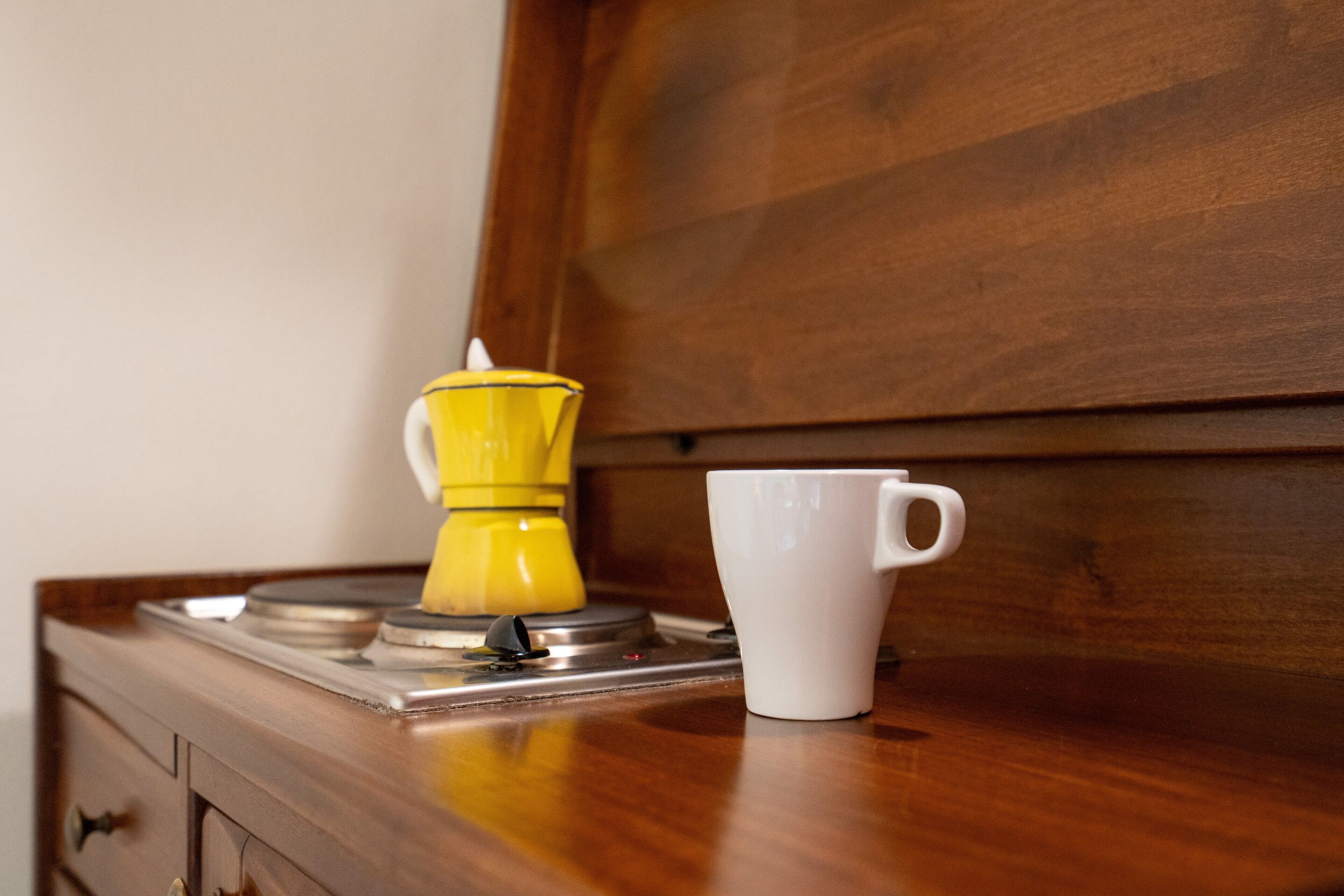 A coffee maker and a mug on a wooden surface.