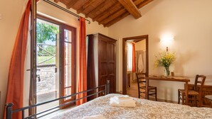 A bedroom with a bed, a desk, a chair, and a bathroom visible through an open door. - Il Bacio – Agriturismo with Experiences, Breakfast Included - Le Ceregne Bio (Pieve Santo Stefano)