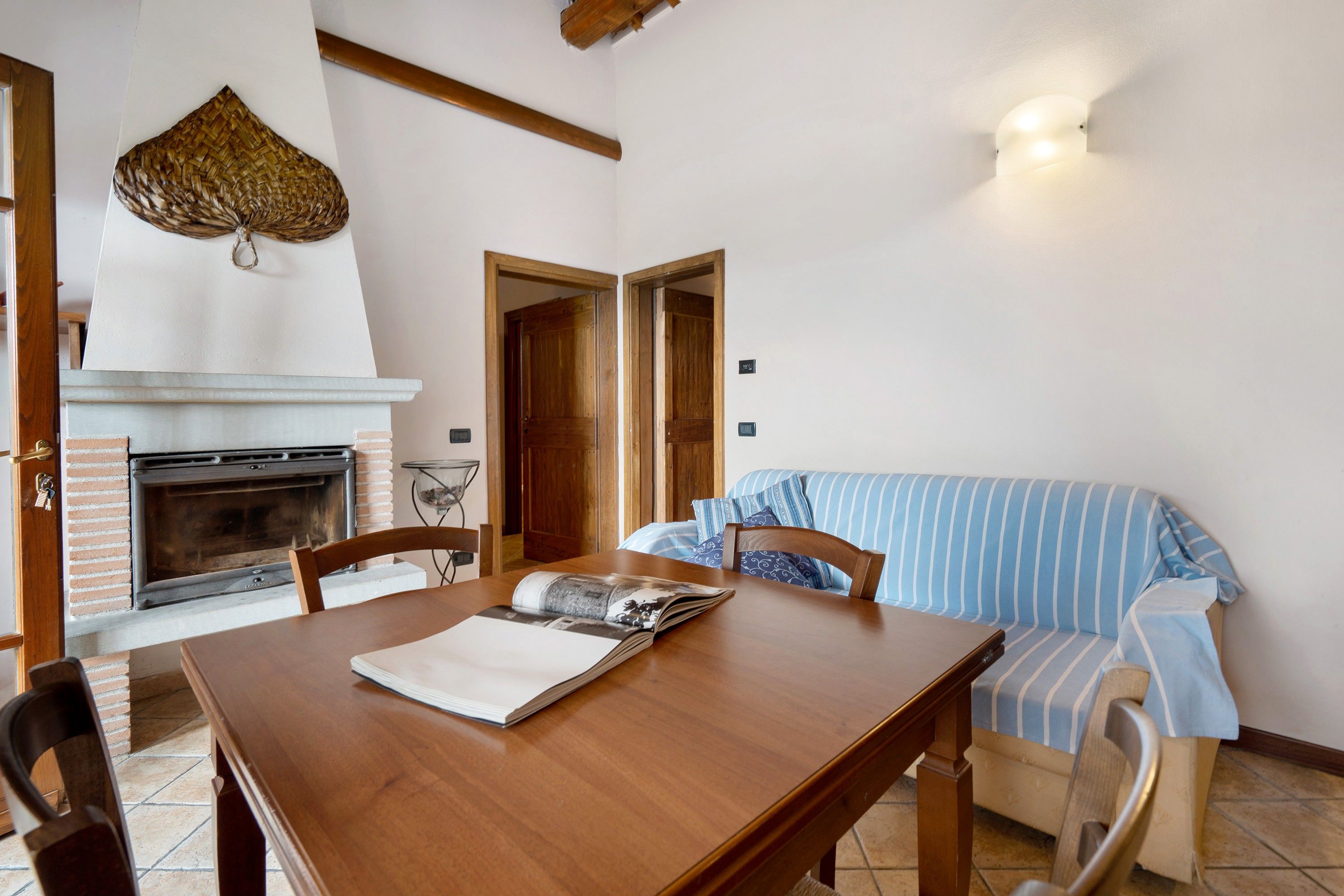 Un coin repas avec une table en bois, des chaises, une cheminée et un canapé à rayures.