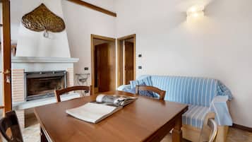 Un coin repas avec une table en bois, des chaises, une cheminée et un canapé à rayures.