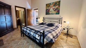 A bedroom with a bed, a nightstand, a painting, and a wooden door. - Dimora delle Fate – Farm Stay with Experiences, Breakfast Included - Le Ceregne Bio (Pieve Santo Stefano)