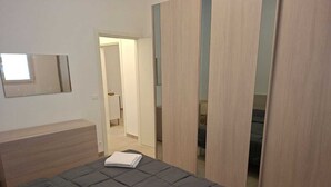 A bedroom with a bed, a dresser, and a wardrobe. - New, detached vacation home near Taranto, ideal for 2-4 people. (Montemesola)