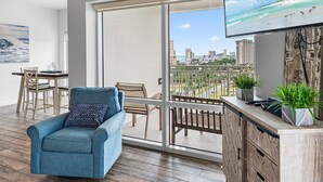 A balcony with a city view, a sofa, a dining table with chairs, and a TV mounted on the wall. - Luau II 6924 (Miramar Beach)