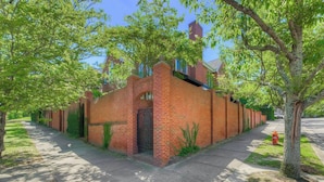 A row of brick houses with a central entrance gate, surrounded by trees and a sidewalk. - The Landing at Wheat St.| 2Br in the heart of USC (Columbia)
