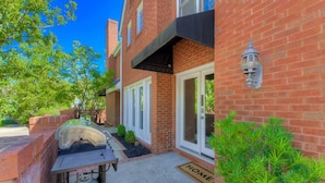 A residential building with a brick facade, a garage door, and a small garden area with a doormat. - The Landing at Wheat St.| 2Br in the heart of USC (Columbia)