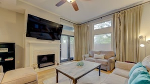 A living room with a fireplace, a sofa, a coffee table, and a television mounted above the fireplace. - The Landing at Wheat St.| 2Br in the heart of USC (Columbia)