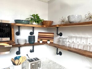 A kitchen with wooden shelves, a microwave, a toaster, and various kitchenware. - Cece's Chalet: Hot Tub * New Owner Offer (Mount Jackson)