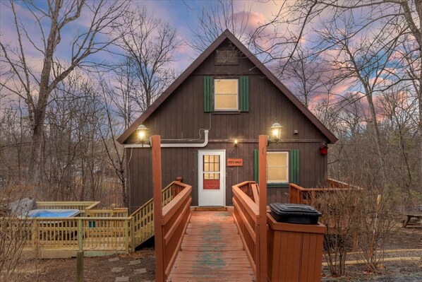 A wooden cabin with a porch, a door, and a sign indicating a sauna. - Cece's Chalet: Hot Tub * New Owner Offer (Mount Jackson)